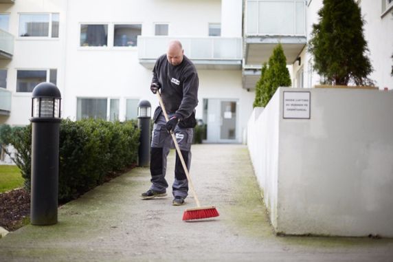 Vaktmester som feiier et uteområde